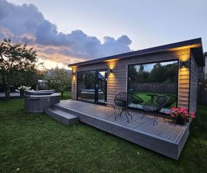 a house with a deck with a table and chairs at Kursīšu namiņš in Skulte