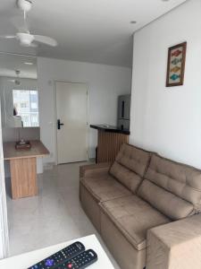 a living room with a brown couch and a kitchen at Refúgio Brisa e Mar in Mongaguá