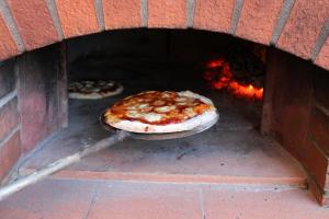 two pizzas are cooking in a brick oven at Casa l'Oca in Figline Valdarno
