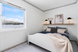 a white bedroom with a bed and a window at Nordnorge Self-Check-In in Majavatn