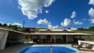 a villa with a swimming pool in front of a house at Recanto Vó Rosa in Socorro