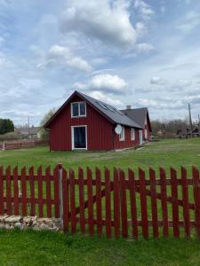 a red barn in a field with a fence at Vesilinnu 2 in Aabla