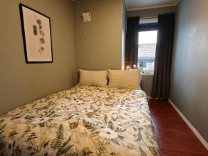 een slaapkamer met een bed met een bloemenbed en een raam bij Bright & Spacious Apartment by the Sea, Free Parking, 10min to Airport, 12min to Ålesund in Ytterland
