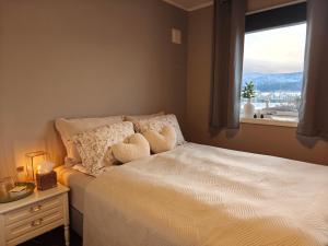 a bedroom with a bed with two pillows and a window at Bright & Spacious Apartment by the Sea, Free Parking, 10min to Airport, 12min to Ålesund in Ytterland
