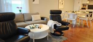 een woonkamer met een bank, stoelen en een tafel bij Bright & Spacious Apartment by the Sea, Free Parking, 10min to Airport, 12min to Ålesund in Ytterland