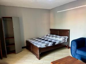 a bedroom with a bed and a blue couch at Stylish Smart Studio Apartment in Kampala +9 photos