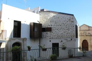 an old stone building with windows and a fence at Le Dimore di San Nicola in Favara