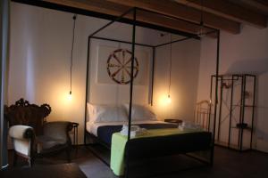 a bedroom with a canopy bed with a chair and a table at Le Dimore di San Nicola in Favara