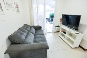 a living room with a gray couch and a tv at Tree Bies Resort - Refúgio a beira-mar in Entre Rios