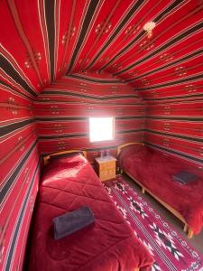 a room with two beds in a red room at Wadi Rum Desert Experience in Wadi Rum