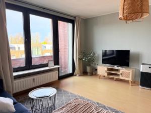 a living room with a flat screen tv and large windows at Schöne 3-Zimmer City-Wohnung in Neumünster