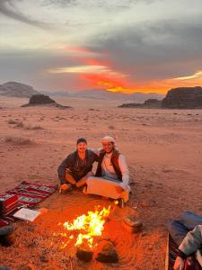 瓦迪拉姆Wadi Rum Desert Experience的沙漠中，一男一女围坐在篝火旁。