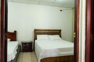 哥伦比亚港Donde Mire的一间卧室配有两张带白色床单的床和一扇门 更多9张照片