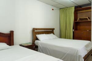 哥伦比亚港Donde Mire的一间卧室，有两张床和一扇带绿色窗帘的窗户