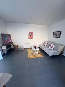 een woonkamer met een bank en een tafel bij Maison entière avec jardin , Proche Bordeaux, Rocade et Arkéa Arena in Bouliac