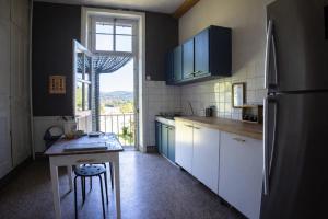 a kitchen with a refrigerator and a table in it at Le Cœur d'Estourgie in Pionsat