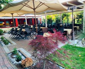 a patio with tables and chairs under an umbrella at Hotel Oasi Este in Este