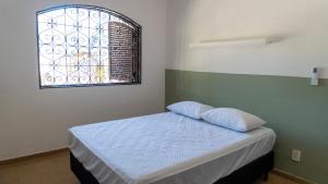 a small bedroom with a bed with a window at Casa Itaguá in Ubatuba