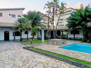 a house with a swimming pool and palm trees at Casa Itaguá in Ubatuba