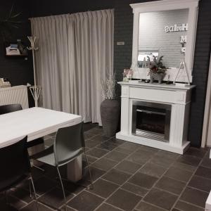 een woonkamer met een open haard en een tafel met stoelen bij Voormalige Gevangenis Cel bij B&B Gezond aan Zee - Toegang Wellnesstuin meerprijs in Ouddorp