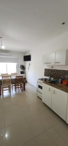 a kitchen with white cabinets and a dining room with a table at Pewmafe in Las Grutas