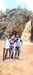 een groep van drie personen die voor een waterval staan bij Homebase gardens guesthouse in Nakuru