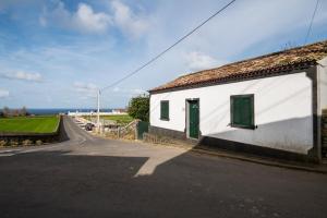 a white building with a green door on the side of a road at Rustic House - Eco Farm Living in Capelas
