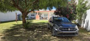 a car parked under a tree in front of a house at Pewmafe in Las Grutas