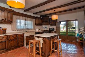 una cucina con armadi in legno e un'isola con sgabelli di Casa com Piscina Privada em Palmela - Jardim & Estacionamento a Palmela