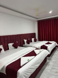 two beds in a hotel room with red curtains at Breezy bluff in Madikeri