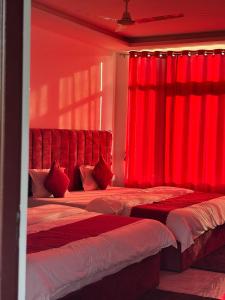 two beds in a room with red curtains at Breezy bluff in Madikeri +4 photos