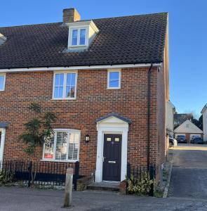 a red brick house with a black door at Siskin House in Wickham Market