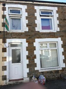 a brick building with a white door and two windows at Treforest Cwtch House in Treforest