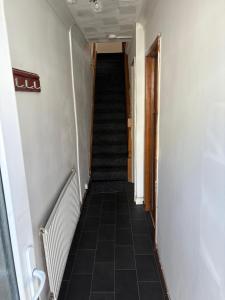 a hallway with a staircase with black tiled floors at Treforest Cwtch House in Treforest