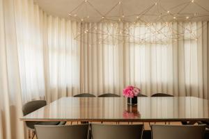 a table with chairs and a vase of pink flowers at Villa-Sabbia in Koksijde