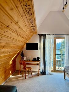 een woonkamer met een bureau en een groot raam bij Rezydencja Kojsowka in Witów