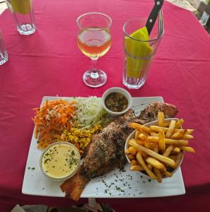 a plate of fish and french fries and a glass of wine at Bien venu Miss' K in Anse-Bertrand
