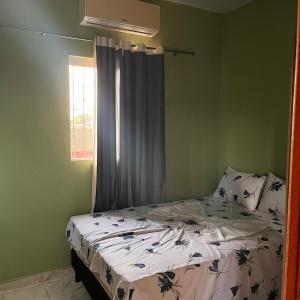 a bed in a green bedroom with a window at Casa do Will in Ananindeua