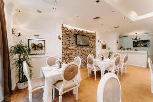 una sala da pranzo con tavoli e sedie bianchi e un muro in pietra di Golden Hotel a Pristina