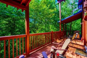 a porch of a cabin with chairs and trees at Goonies Cove - Spacious 4BR Cabin Arcade, Pool Table & Hot Tub! in Sevierville