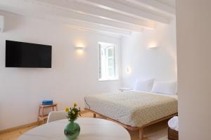 a white bedroom with a bed and a tv at Galaxidaki στην Πλατεία in Galaxidi