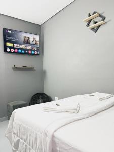 a bedroom with a white bed with a tv on the wall at Hostel Anprado #5 Kit café incluso, Próx-Aeroporto de Guarulhos in Guarulhos +9 photos