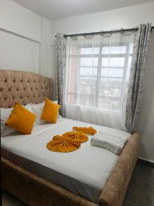 a bed with orange and white sheets and a window at EnE Homes in Kisumu