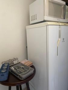 a microwave on top of a refrigerator with a table at Quarto suíte privativa in Xaxim