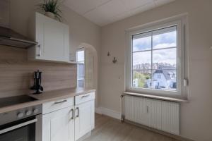 a kitchen with white cabinets and a large window at Haus Strandkrabbe, Seehund in Döse