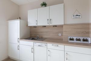 a kitchen with white cabinets and a sink at Haus Strandkrabbe, Seehund in Döse