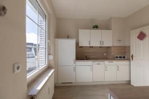 a kitchen with white cabinets and a large window at Haus Strandkrabbe, Seehund in Döse