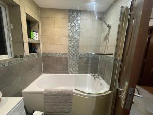 een badkamer met een bad en een douche bij 4-Bed Barnwell Retreat- Sleeps10 Garden & Parking in Stevenage +47 foto's