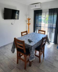 a dining room table with four chairs and a tv at Departamento Tunuyan in Monte Hermoso