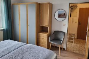 a bedroom with a bed and a chair and a mirror at Haus Hinter der Kirche in Döse +23 photos